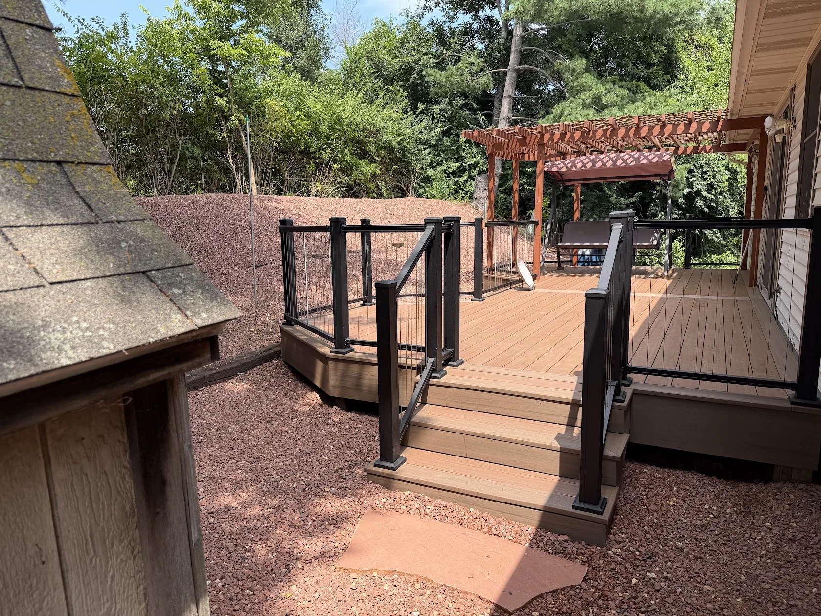 Composite deck with black railings, steps and a pergola.